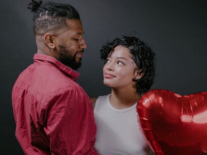 Casal olhando um para o outro enquanto segura um balão vermelho em forma de coração