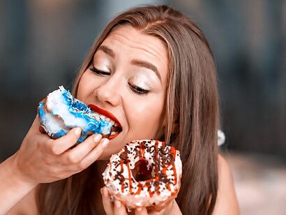 Young woman craving a box of delicious donuts, illustrating food cravings and indulgent eating habits