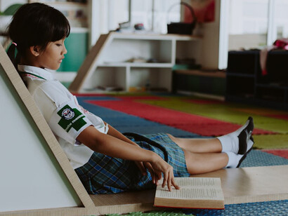 Girl at school sits and reads a book, learning how to master her mind and develop her concentration