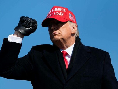 Donald Trump raises his fist while donning the MAGA cap