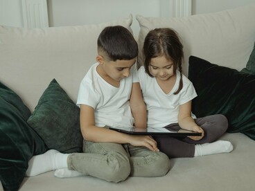 Uma menina e um menino utilizam juntos um dispositivo digital, concentrados naquilo que aparece diante deles. Mais do que oferecer acesso individual à informação, a tecnologia também pode se tornar instrumento de interação, descoberta e aprendizagem compartilhada
