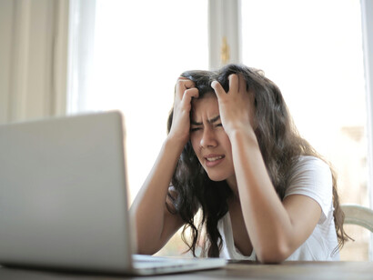 A woman distressed about something she sees on the screen, reflecting how there are various stressors in our daily lives that can trigger strong emotional reactions and have a negative impact on our health