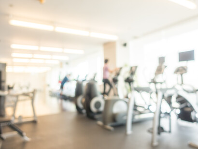 Una palestra moderna con macchine per l'allenamento cardio e pesi, mostrata con un effetto sfocato