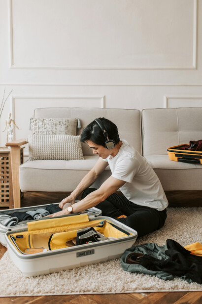 Man wearing headphones and packing for a trip, representing a travel blogger lifestyle