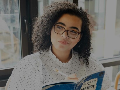 A woman smirking as she might have just untangled the web of uncertainty while jotting down on her notebook