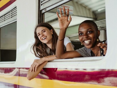 Women talking on a train, one gazing out the window