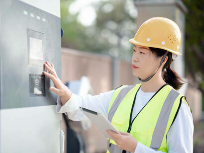 An Asian electrical technician in his middle years working at an electric vehicle charging station