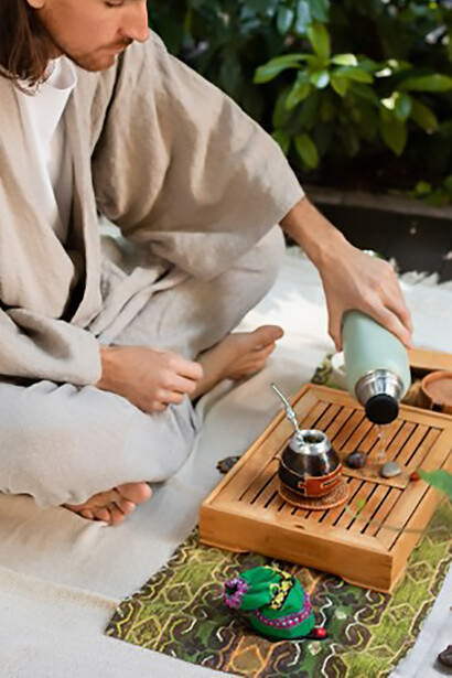 A man holding a cup of herbal tea in a natural setting, reflecting the Ayurvedic approach to wellness
