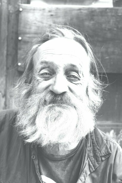 Poor man with long beard looks into the camera