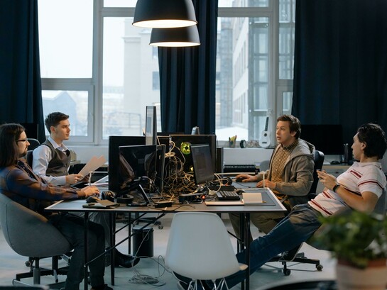 Quatro homens trabalham em frente a computadores num ambiente de escritório. A baixa diversidade nas equipas que desenvolvem inteligência artificial é apontada por especialistas como um dos fatores que contribuem para pontos cegos e vieses nos sistemas. O artigo discute como as escolhas de quem cria a IA influenciam os resultados produzidos pelos algoritmos. A predominância masculina em áreas ligadas à inteligência artificial continua a ser um desafio para a diversidade de perspectivas no setor