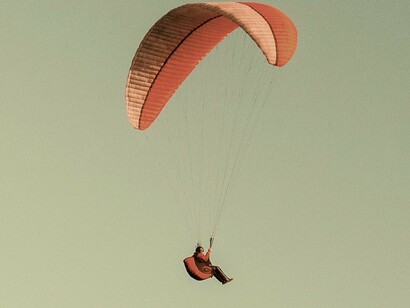 Vôo de parapente. À medida que Nina se prepara para o tão sonhado salto, o clima esboça uma leve mudança. O piloto da asa delta a apressa e saem os dois correndo pela rampa para se lançarem no precipício
