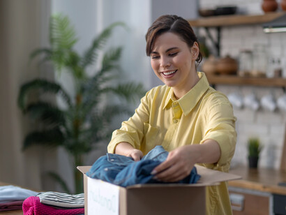 A woman, carefully packing clothes for donation as part of a wardrobe clean-out