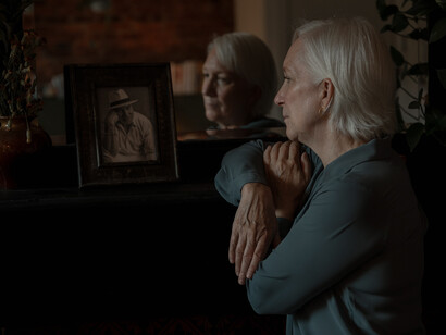An aged woman's mournful gaze fixates upon a photograph, her heart burdened with grief, a tangible manifestation of her profound sadness and bereavement