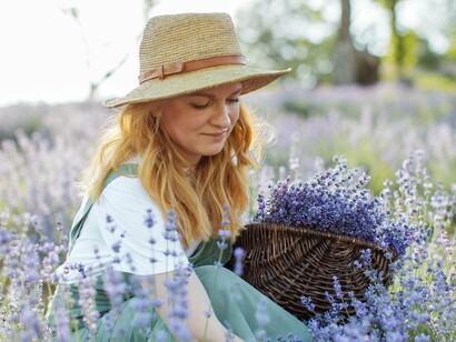 Amid a lavender field, a woman collects flowers in a woven basket, immersed in the rhythm of nature—a reminder that not everything needs to serve a function
