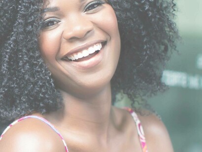 A woman smiling and wearing western clothing indicates a shift in her culture from African to Western