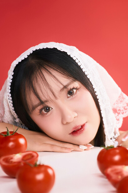 A playful portrait of a woman with tomatoes against a bold red backdrop