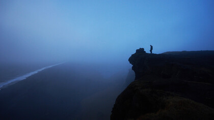 Hombre camina sobre un risco hacia un abismo frente al mar