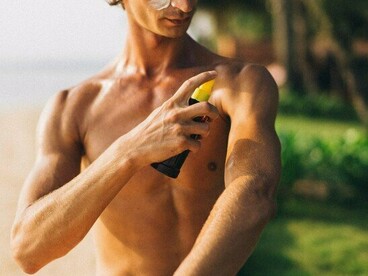 A person shielding their skin with sunscreen before enjoying the sunshine, reflecting the first line of defense against UV damage