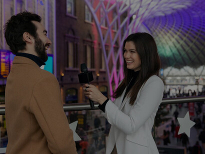Outdoor scene featuring a smiling reporter with a man
