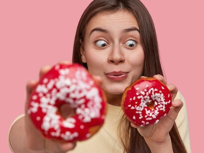 A woman gazing at a doughnut with intense longing, revealing her struggle with sugar addiction
