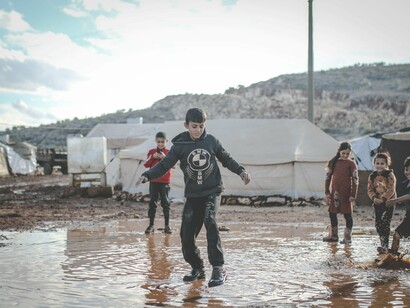Children playing on a muddy area. Poverty extends beyond material possessions