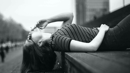 A woman lying down on the street smoking a cigarette