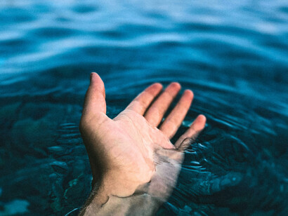 La main immergée dans l'eau illustre la continuité entre la matière et la conscience, représentant l'unité des différentes strates naturelles dans un seul monde