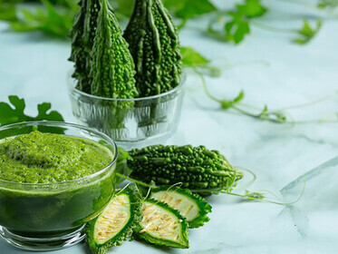 Glass of refreshing bitter gourd smoothie garnished with chopped bitter gourd