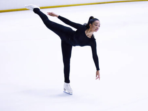 A girl performing a graceful figure skating routine on the glistening white ice