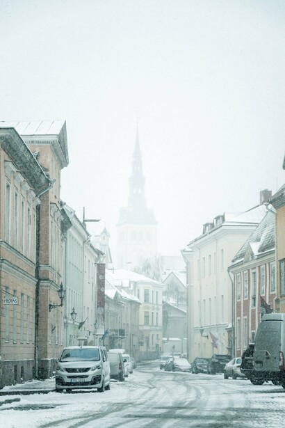 A snowy street lines with cars and vans