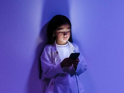 A young girl fixated on her smartphone, representing the growing dependence of younger generations on digital technology