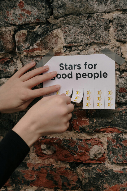 A hand pulls off a paper note from the wall of stars, symbolizing recognition and motivation