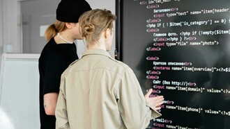 Two men reviewing code on a board, illustrating collaborative coding and the use of AI tools in development