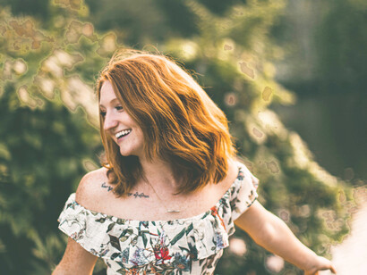 A happy woman dancing in the forest, regaining her place at the center of the world with her will