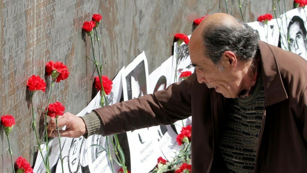Un hombre deposita una flor ante un altar en recuerdo a los desaparecidos en Chile