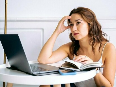 A professional sitting overwhelmed beside her laptop and notes, symbolising the hidden distraction caused by personal financial pressures