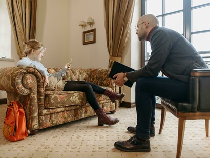 A man, acting in his role as a life coach, speaks calmly and attentively with a woman, helping her reflect on her goals and encouraging her to find clarity