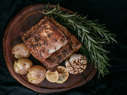 On a rustic wooden board, a perfectly cooked piece of meat is artfully arranged alongside tender potatoes, garlic and a vibrant slice of lemon, creating a harmonious culinary tableau