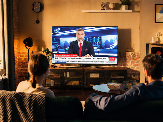 Young couple watching the latest news on television in a cozy loft apartment
