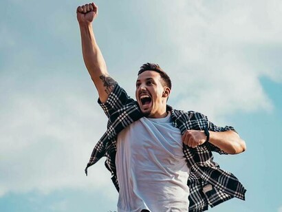 A man jumping for joy and happiness with a fist bump to the sky 