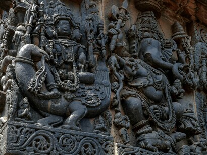 Ornate sculptures of gods decorating the temple walls in Shri Hoysaleswara Temple, Karnataka, representing the continuity of faith across generations