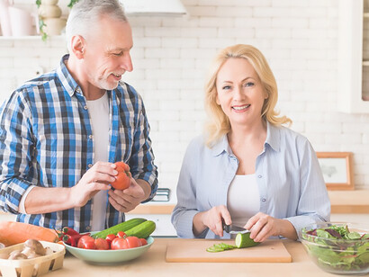 Promote healthy living and family connections with a portrait of a senior man observing his wife's vegetable preparation in a modern kitchen, encapsulating the essence of wholesome living and togetherness
