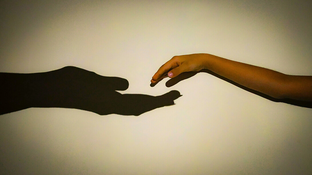 Entre ombres et lumières, attachement et liberté, deux mains cherchent leur juste distance