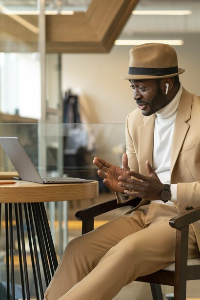A stylish man focused on his laptop in a café, reflecting the importance of competence beyond first impressions
