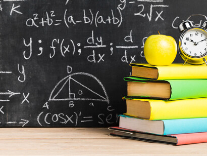 Libros de colores frente a un pizarrón negro, representando la educación tradicional. Los modelos educativos evolucionan con el avance tecnológico