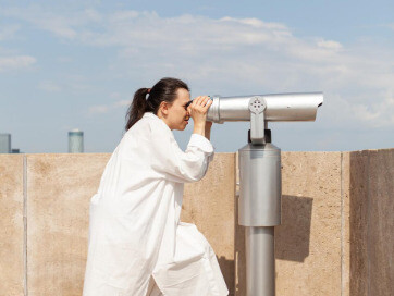 A scientist conducts visual sky surveillance with optical equipment, mirroring the team’s use of layered observation methods across different wavelengths