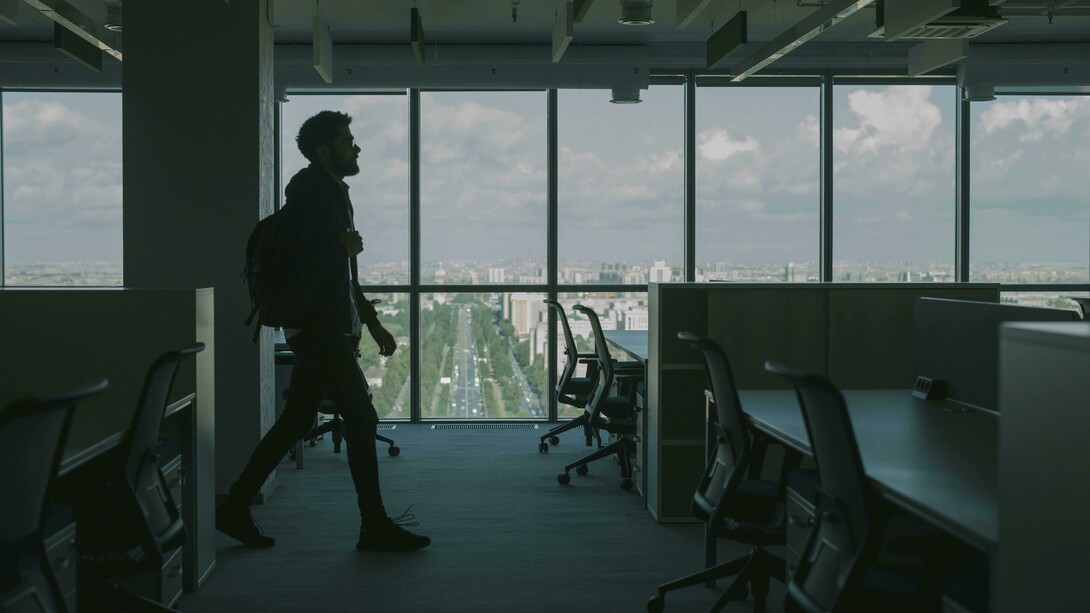A man in a black jacket walking through an empty office