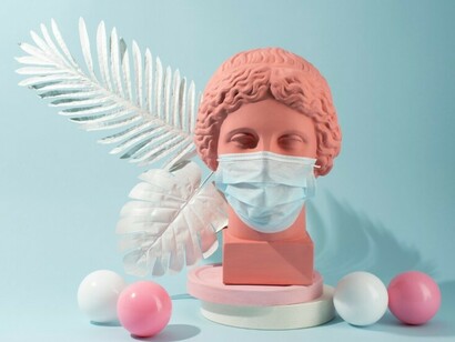 A marble bust of a historical figure adorned with a surgical mask, evoking themes of timelessness and pandemic-era surrealism