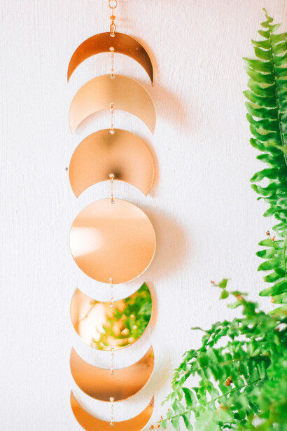 A series of gold-toned discs representing the moon's phases, hanging vertically