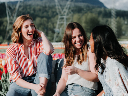 Three friends laughing together while surrounded by a field of tulips